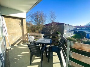 A balcony with a table and chairs, a brick wall, and a view of neighboring buildings. - Holiday Apartment in Westkapelle With Wi-fi (Westkapelle)