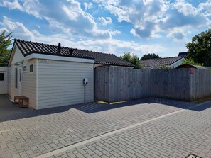 A building with a tiled roof, a wooden fence, and a paved ground. - Ok17 Holiday Home Oostkapelle (Oostkapelle)