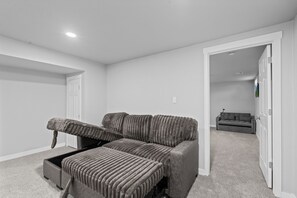 A spacious room with a large bed, a sofa, and a television. - Downtown Retreat for 12 with Air Hockey (Colorado Springs)