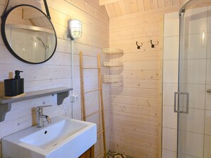 A bathroom with a white sink, a mirror, a shower, and a towel rack. - Holiday Home With 1 Bedroom (Grijpskerke)