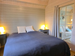 A bedroom with a large bed, two bedside tables with lamps, and a window with curtains. - Holiday Home With 1 Bedroom (Grijpskerke)