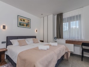Ein modernes Hotelzimmer mit einem großen Bett, einem Schreibtisch, einem Stuhl und einem fenster mit Vorhängen.