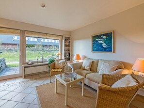 A living room with a sofa, two chairs, a coffee table, a bookshelf, and a painting. - Small Sea Suite (Kampen)