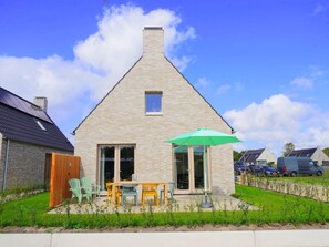 A single-story house with a sloped roof, a small window, and a patio area with outdoor furniture. - Holiday Home Zone (Callantsoog)