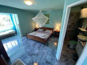 A bedroom with a bed, bedside tables, a window with curtains, and a bathroom with a toilet and sink. - Villa Agata With Private Pool and Sauna (Rab)