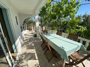 An outdoor patio with a table and chairs, a white railing, and greenery in the background. - Villa Agata With Private Pool and Sauna (Rab)