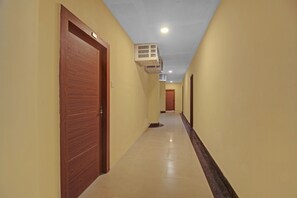 Corredor com portas de madeira, aparelhos de ar condicionado e piso ladrilhado.