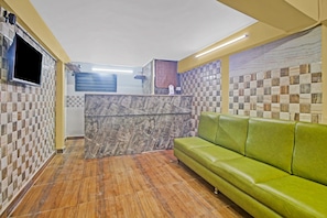 Una zona de recepción con piso a cuadros, un sofá verde y una encimera de mármol.