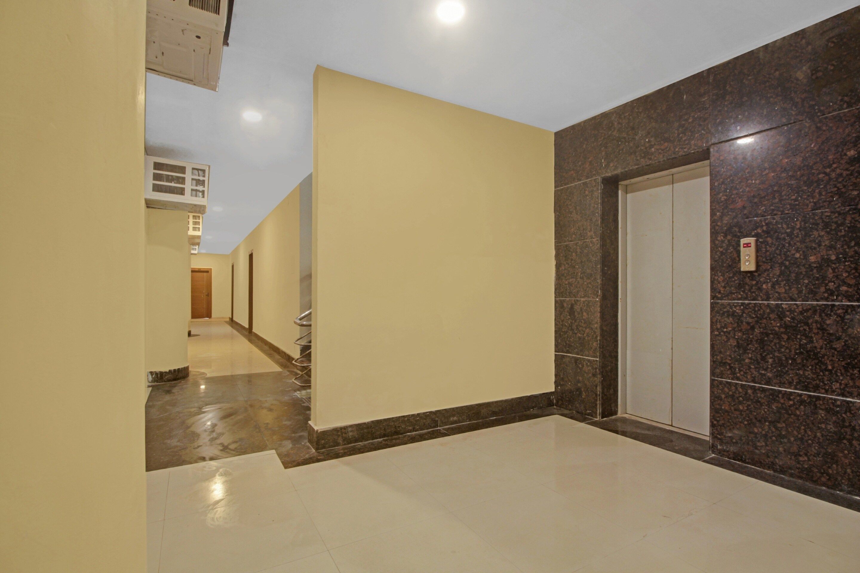 A corridor with a marble floor, a door with a control panel, and a wall with a textured pattern.