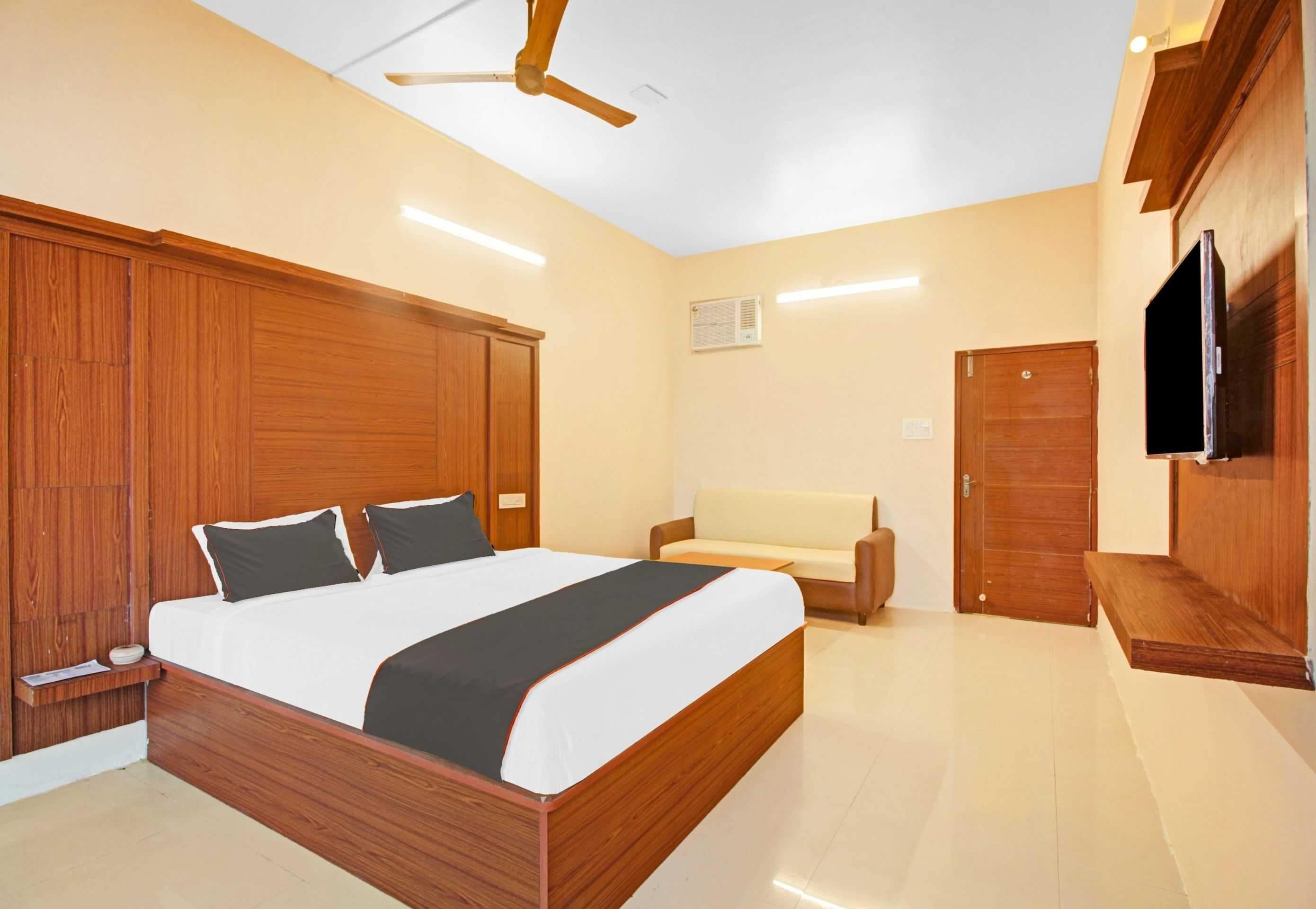 Un dormitorio con cama de madera, un sofá, un televisor y un ventilador de techo.