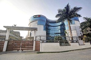 Um edifício moderno com fachada curva, uma placa chamativa com a inscrição 'OYO' e uma entrada com portão.