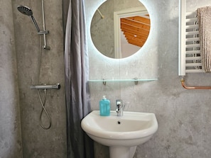 A bathroom with a white sink, a mirror, a shower, and a towel rack. - Do27 Holiday Apartment Near the Center and Beach (Domburg)