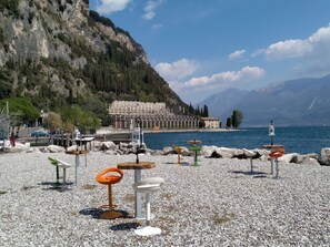 Ein Kiesstrand mit Außenbereich und einem Bergsee im Hintergrund.