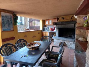 Ein Außenbereich zum Essen mit Tisch und Stühlen, einem Steinkamin und einer Küchenzeile mit einer Mikrowelle.