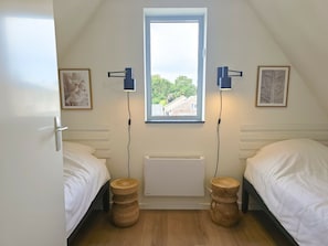 Ein Schlafzimmer mit zwei Betten, einem Fenster und einer Heizung.