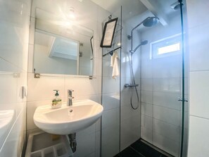 A modern bathroom with a white sink, a mirror, and a glass-enclosed shower area. - Ok03 Bungalow Rocky Docky (Oostkapelle)