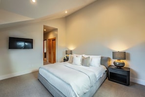 A bedroom with a bed, bedside tables, a TV, and a lamp. - Monthly Lease - Fair View at Old Greenwood by Tahoe Getaways - 5BR w Hot Tub, A/C & EV Charger (Truckee)