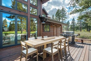 A wooden deck with a dining table and chairs, a barbecue grill, and a glass door leading to a patio area. - Monthly Lease - Fair View at Old Greenwood by Tahoe Getaways - 5BR w Hot Tub, A/C & EV Charger (Truckee)