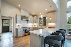 A modern kitchen with a central island, stainless steel appliances, and pendant lighting. - Monthly Lease - Fair View at Old Greenwood by Tahoe Getaways - 5BR w Hot Tub, A/C & EV Charger (Truckee)