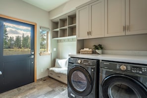 A laundry room with a washing machine, a drying rack, and a window with a view of trees. - Monthly Lease - Fair View at Old Greenwood by Tahoe Getaways - 5BR w Hot Tub, A/C & EV Charger (Truckee)