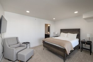 A modern bedroom with a bed, a chair, a bedside table, and a TV mounted on the wall. - New! Monthly Midtown Bozeman Rental + Dogs Welcome (Bozeman)