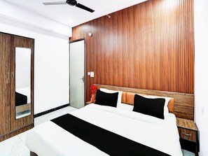 A bedroom with a bed, a wooden wall panel, a ceiling fan, and a door. - Collection O Hotel Star Inn (Ghaziabad)
