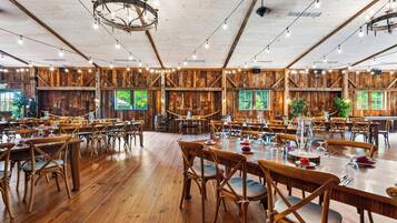 A spacious dining hall with wooden walls and tables set for dining.