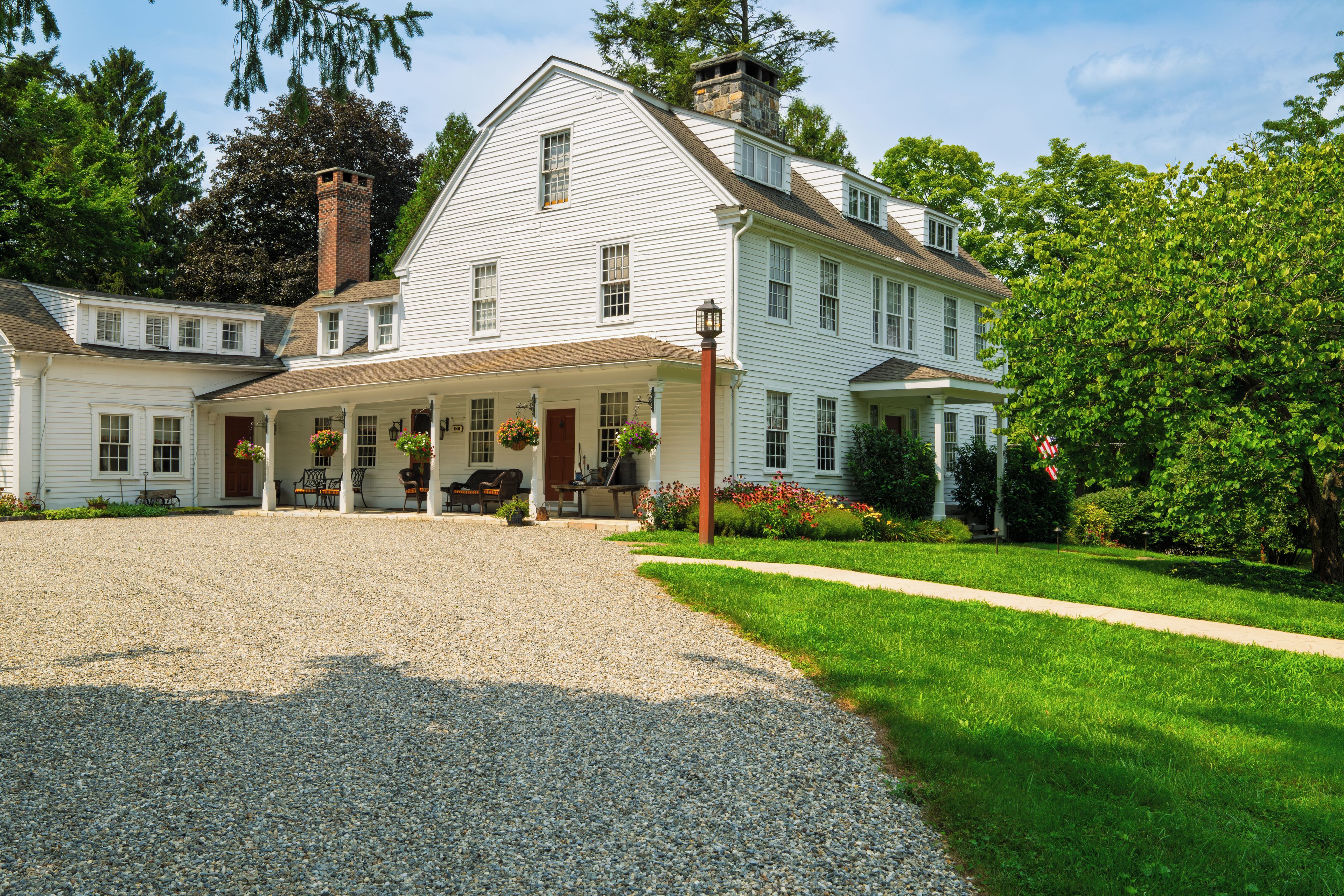 A large white building with a covered porch and a gravel driveway.