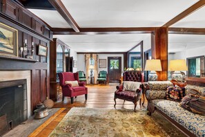 A traditional room with a fireplace, wooden flooring, and classic furniture including a red armchair, a green armchair, and a patterned sofa. - Garden Views + Farm Breakfast + Frette | 1750 Inn | The Rose (Dover Plains)