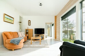 Una sala de estar moderna con un sofá, televisor y mueble de madera.