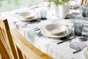 A dining table set with plates, glasses, and cutlery, covered with a patterned tablecloth. - Riverside Log Villa, Sauna By Lapland Host (Rovaniemi)