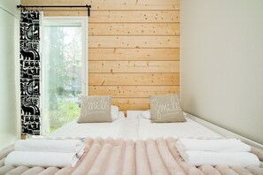 A room with a bed, two pillows with 'Smile!' text, a window with blinds, and a curtain with a black and white pattern. - Riverside Log Villa, Sauna By Lapland Host (Rovaniemi)