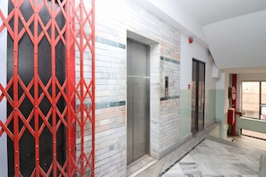 A hallway with a red metal gate, a door, and a tiled wall. - Hotel O Maruti Lodging (Kolkata)