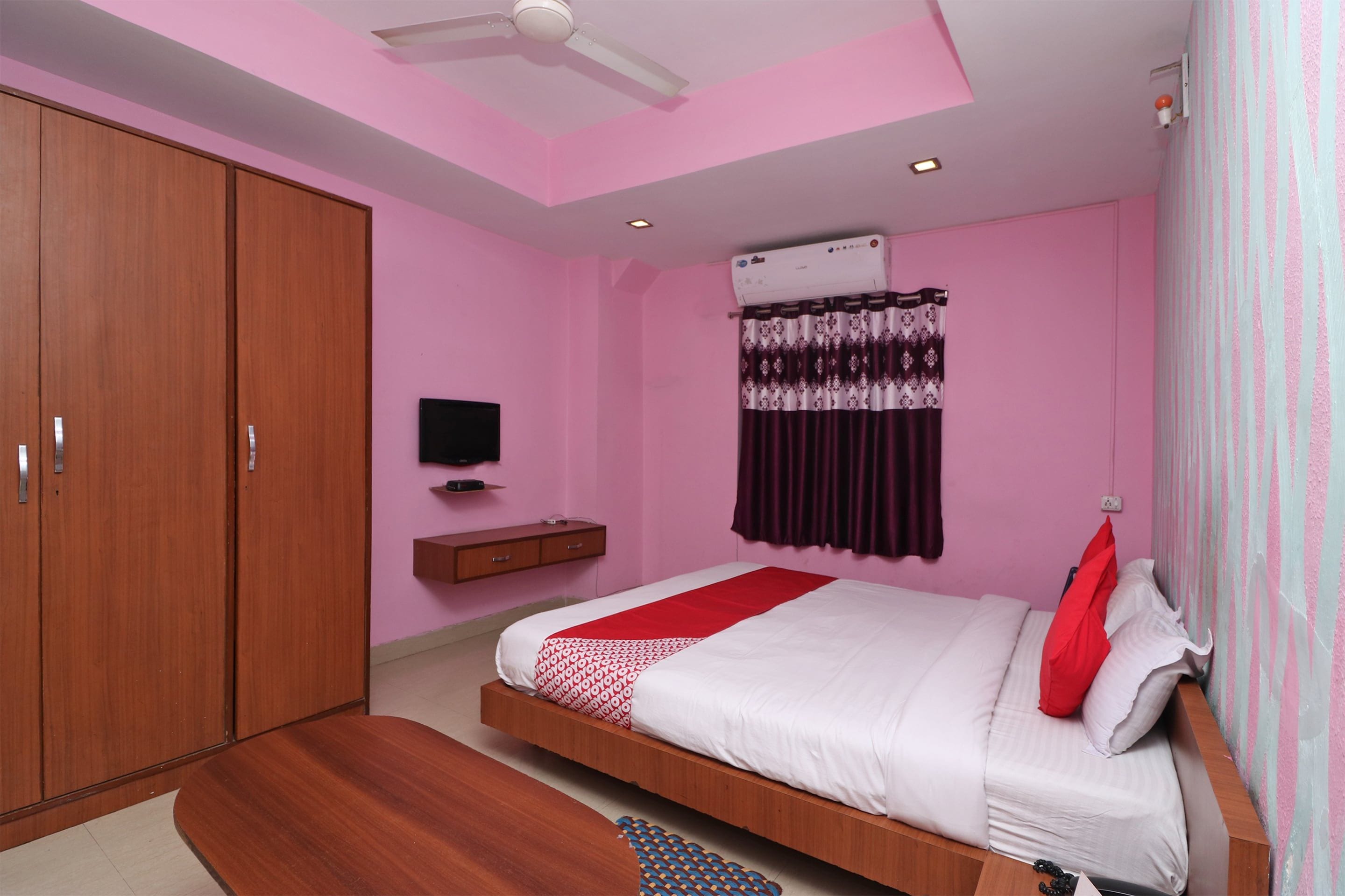 Un dormitorio con cama, armario, televisor y aire acondicionado.
