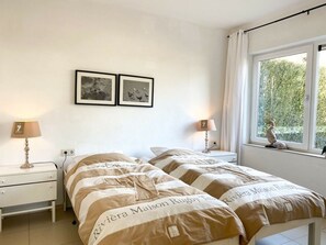 A hotel room with a bed, two bedside tables, a window with a view, and two framed pictures on the wall. - Ok32 Rural Holiday Home (Oostkapelle)