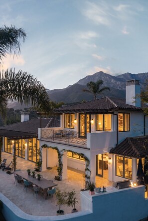 A modern two-story house with a patio area, large windows, and a view of mountains. - Luxury Estate with Infinity Pool & Panoramic Views of Santa Barbara's Coast & Mountains (Santa Barbara)