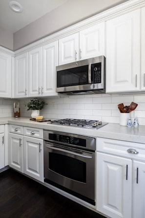 A modern kitchen with white cabinetry, a stainless steel stove, an oven, and a microwave. - Darling Multi-Level Condo with Stunning Mountain Views & Close Proximity to The Beach! (Santa Barbara)