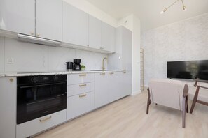 A modern kitchen with white cabinetry, a built-in oven, and a coffee maker. - Warsaw | Zbąszyńska 4 | Spacious Apartment | Balcony (Warszawa)