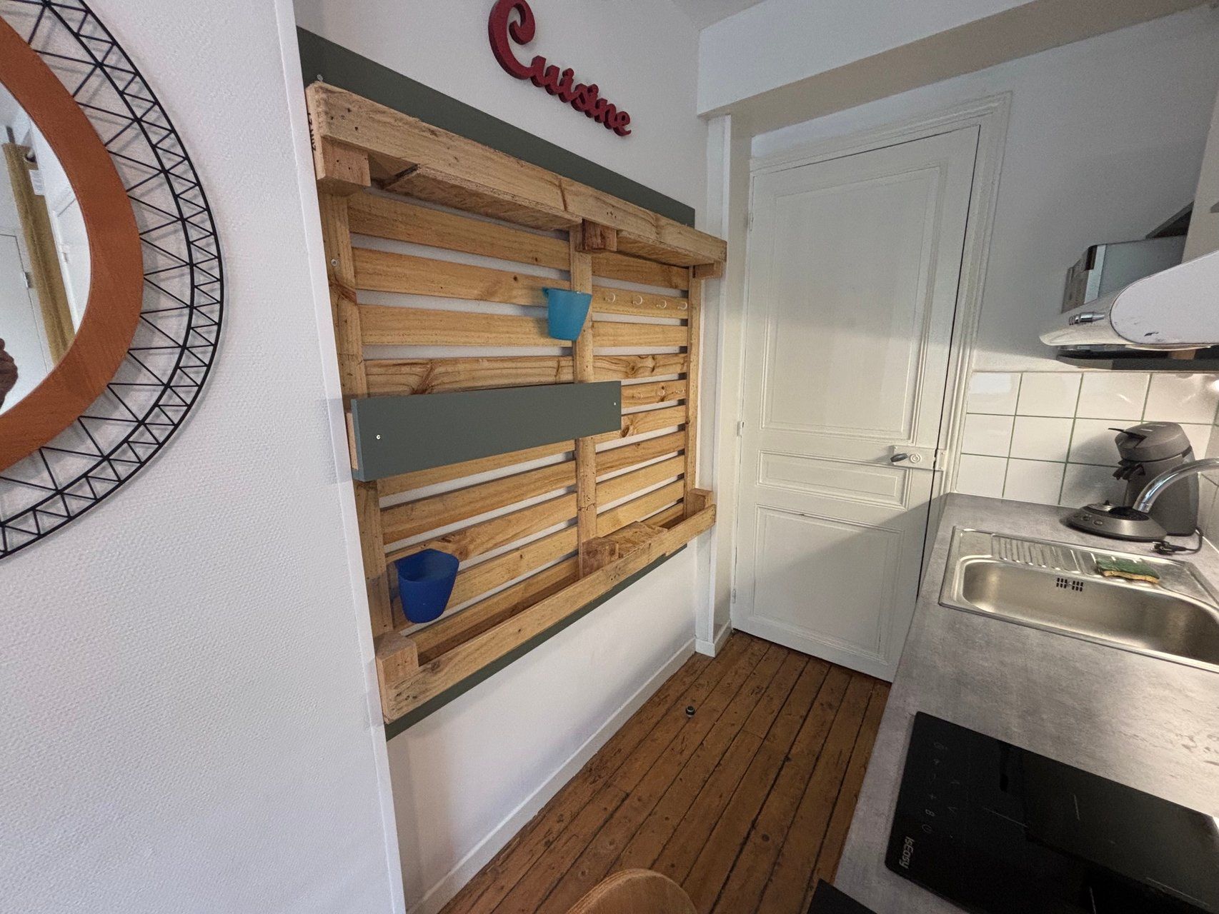 Een keuken met een wand van houten latten, een spoelbak en een aanrecht.