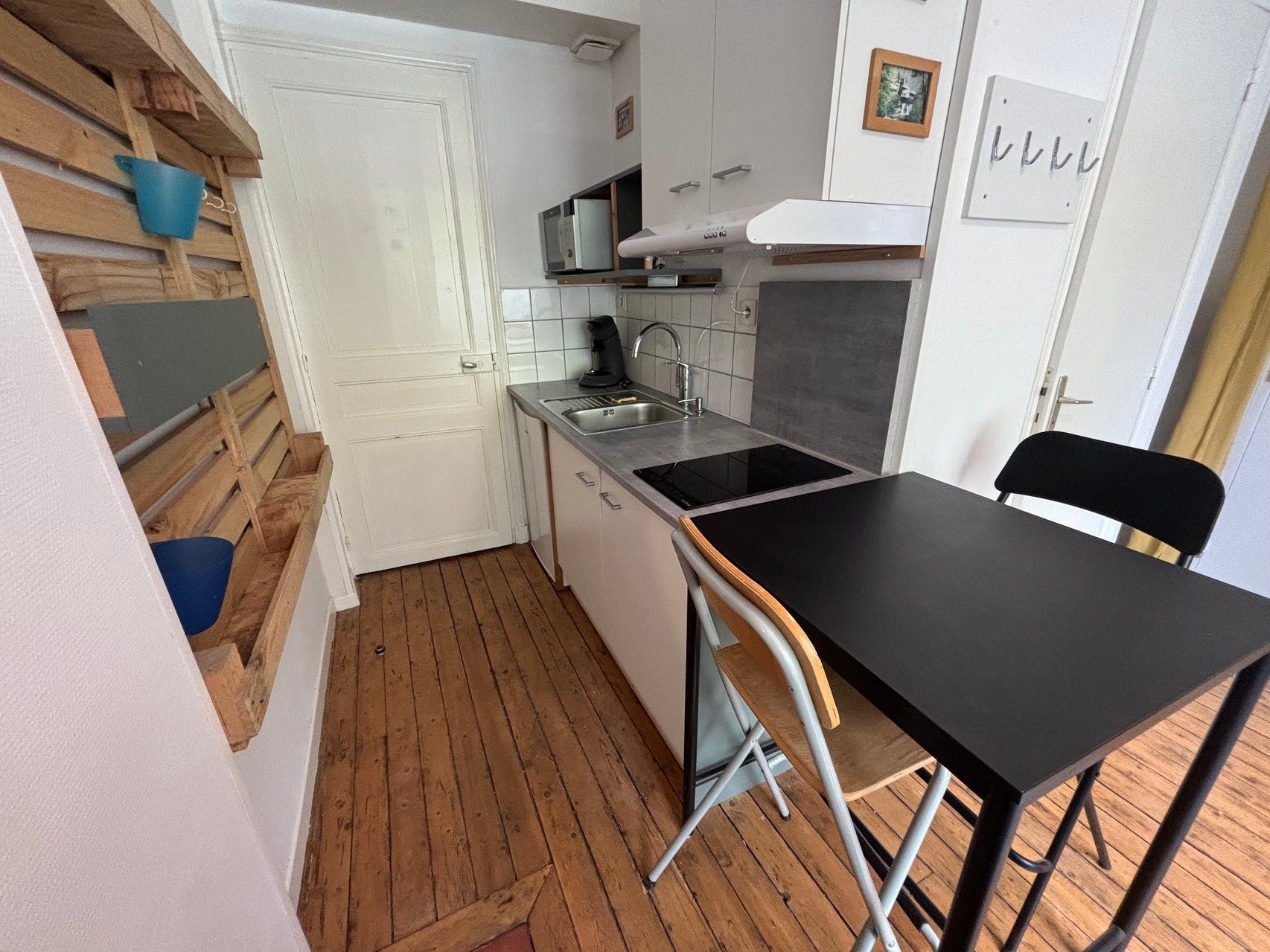 Une cuisine de taille réduite, dotée d’un plan de travail noir, d’un évier et d’un four à micro-ondes.