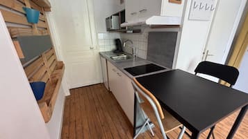 Une cuisine de taille réduite, dotée d’un plan de travail noir, d’un évier et d’un four à micro-ondes.