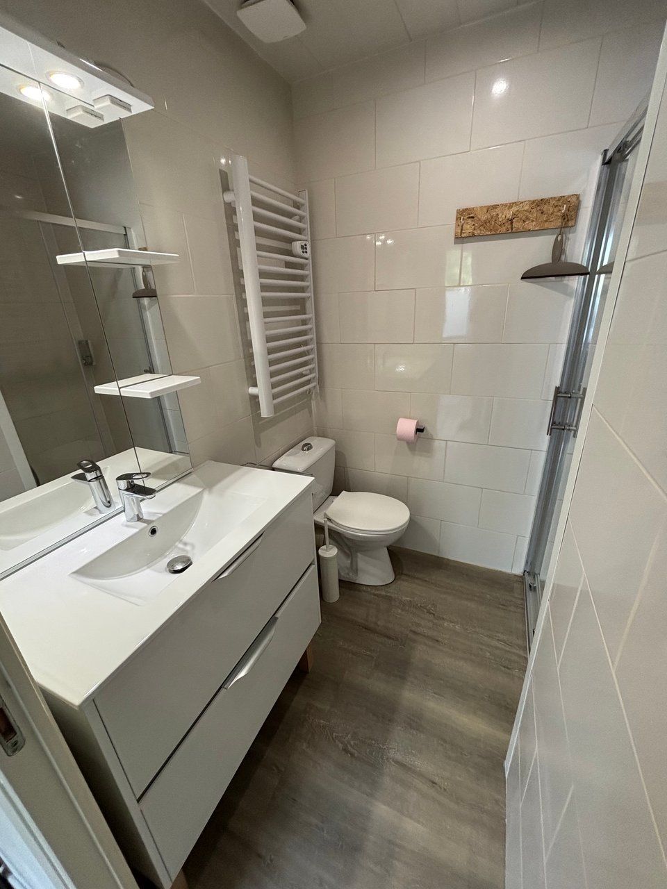Een moderne badkamer met een wit wastafel, toilet en douche.