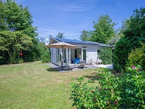 A small house with a patio, a glass door, and a satellite dish. - Holiday Home With 2 Bedrooms (Oosterend)
