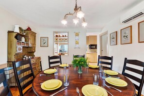 A dining room with a wooden table set for four, surrounded by chairs, with a chandelier above. - Library + Sunroom + Dining for 8 | Ensuite Baths + Gardens | Preston House (74) (Dover Plains)