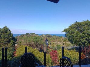 A balcony with a view of a coastal landscape, including trees and a distant view of the sea. - The Tee Box - Stay, Relax & Unwind (Southbroom)