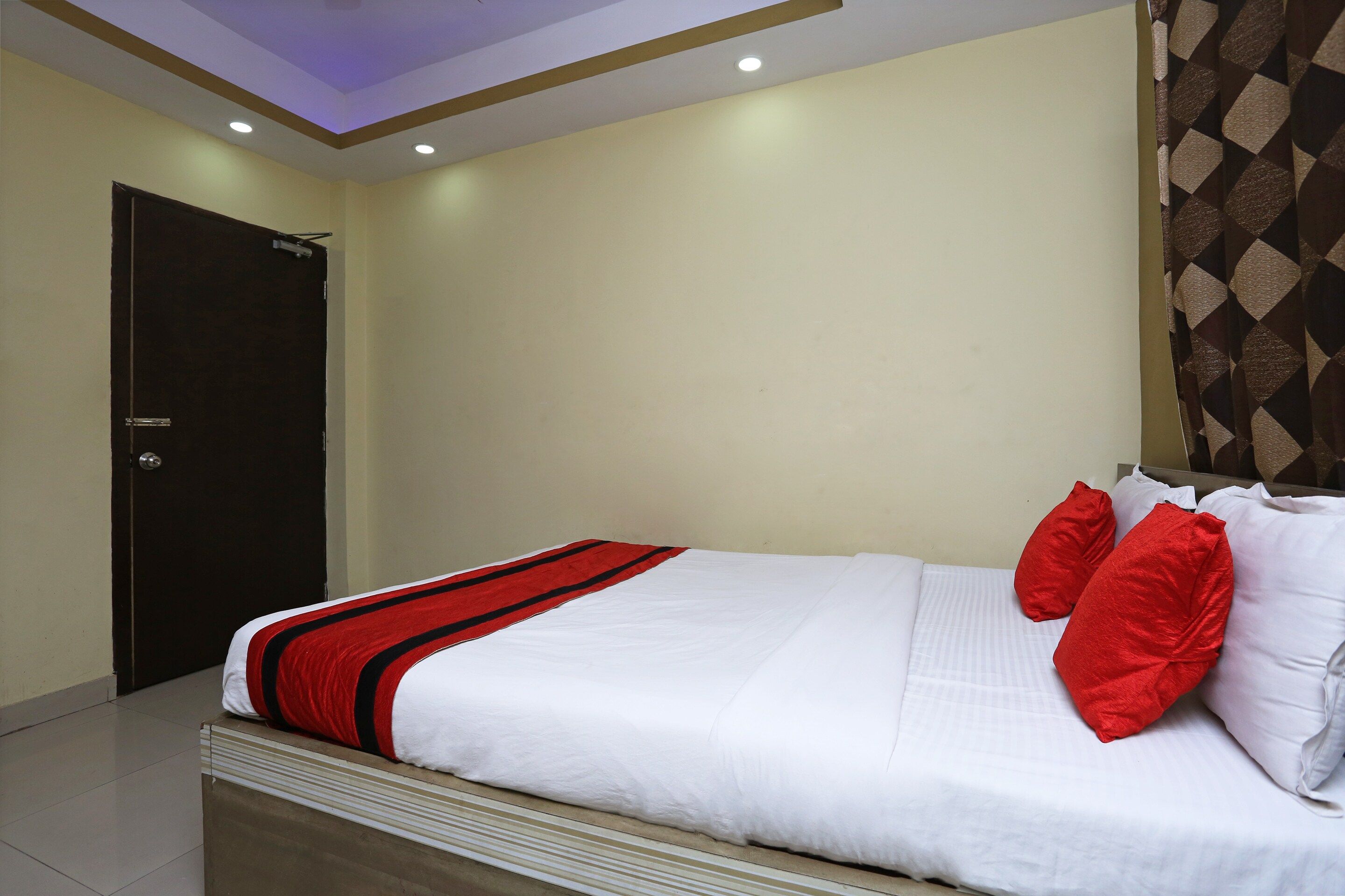 Ein Hotelzimmer mit einem Bett, einer Tür und einem gemusterten Vorhang.
