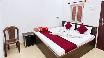 Une chambre d’hôtel avec un lit, une chaise, un appareil de climatisation, une fenêtre avec un rideau et un tapis rouge à motifs.