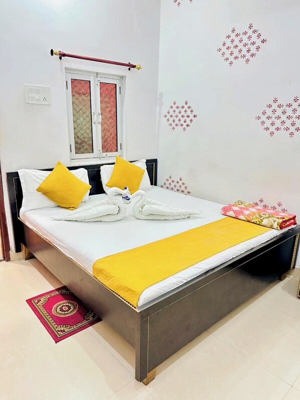 A hotel room with a bed, pillows, a window, and a wall decoration.