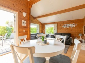 A cozy cabin interior with a round dining table, two sofas, and a large window. - Holiday Home in Renesse With Swimming Pool (Renesse)
