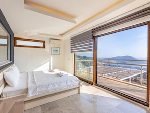 Ein Schlafzimmer mit großem Fenster, einem Bett und Blick auf eine Stadtlandschaft.